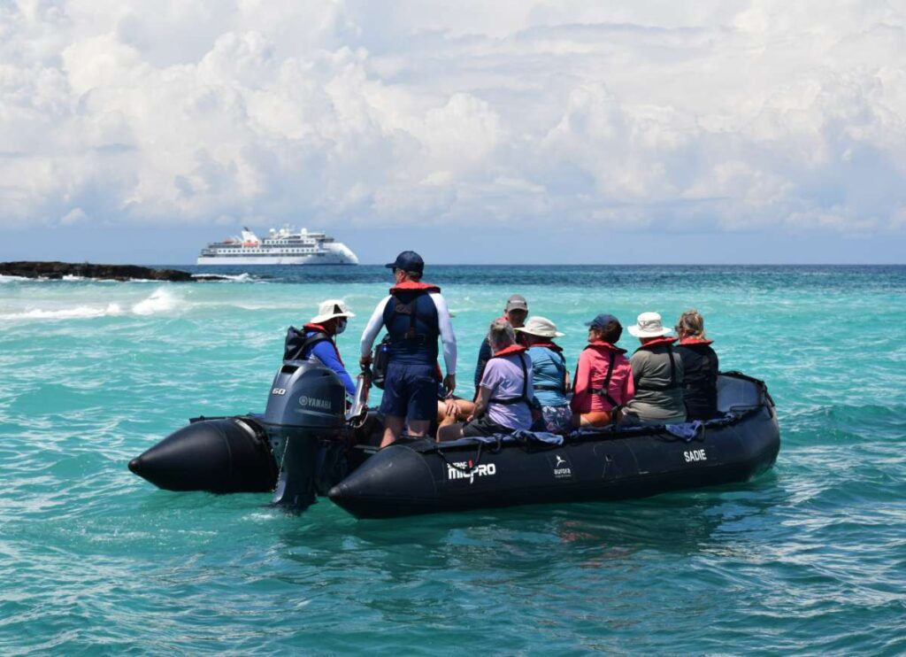 Zodiac cruising with Greg Mortimer in the background, Bartolomé Island, Panama, Conrad Weston